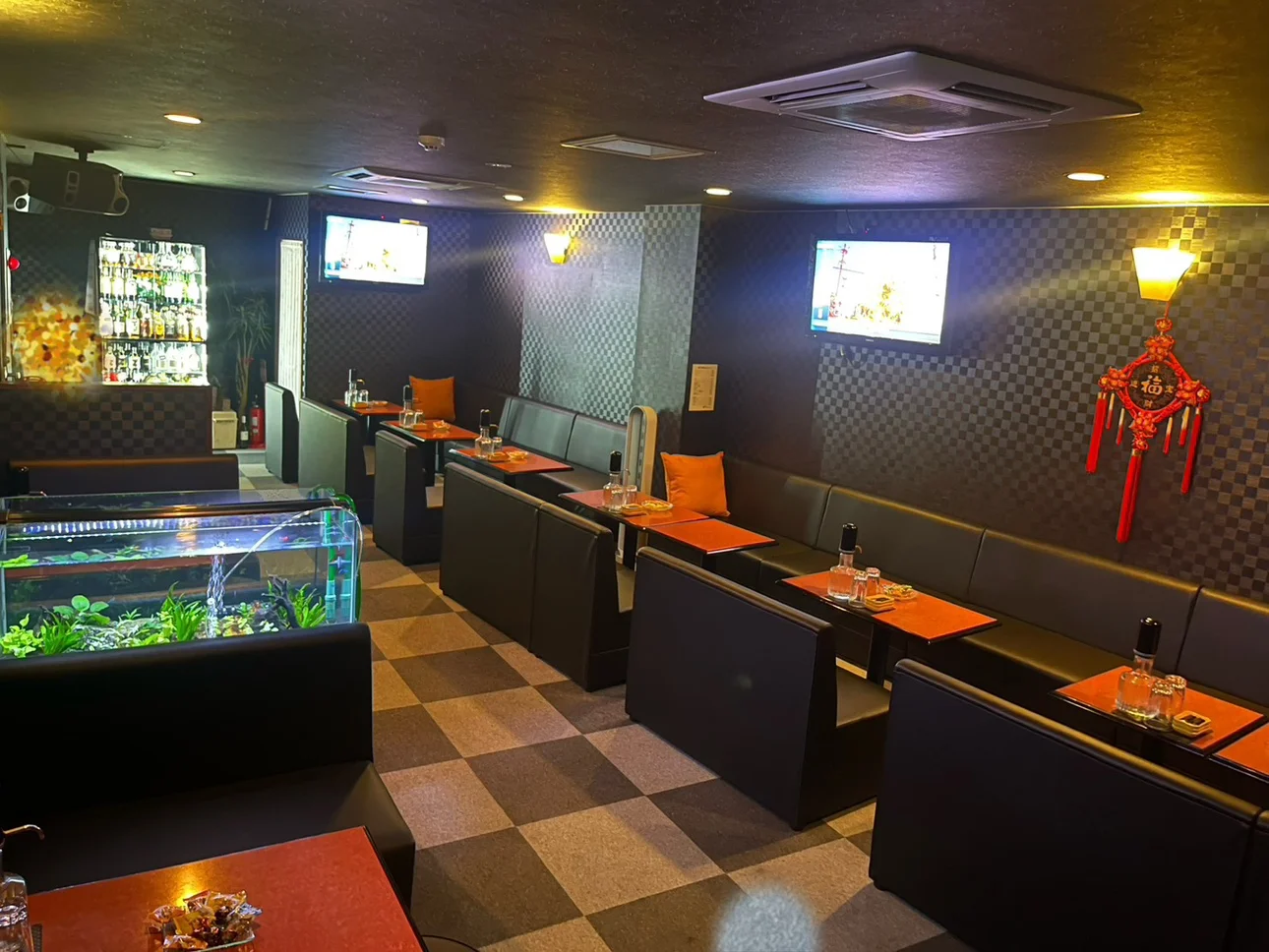 暖かな照明の下に黒いボックス席と赤茶色のテーブルが並ぶ店内